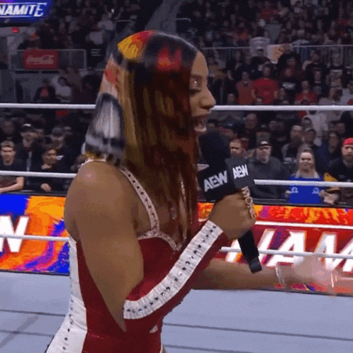 a woman in a wrestling ring is holding a microphone that says aew