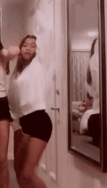 a woman is standing in front of a mirror in a room .