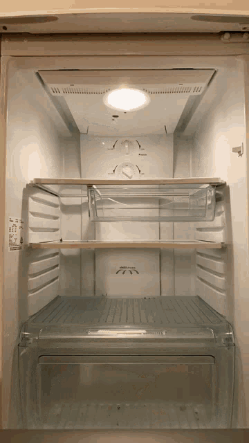 the inside of an empty refrigerator with a light on the bottom shelf