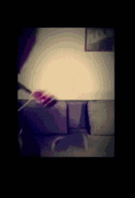 a person is standing in front of a couch holding a remote control