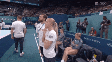 a group of people standing in a stadium with a sign that says paris 2024