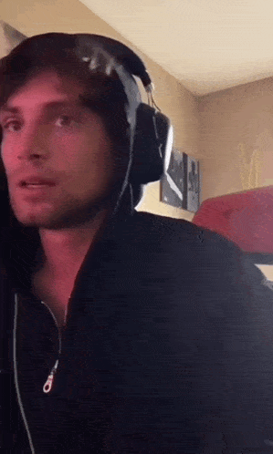 a man wearing headphones and a hooded jacket is looking at the camera .