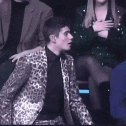 a man in a leopard print suit is sitting next to a woman in a black dress .