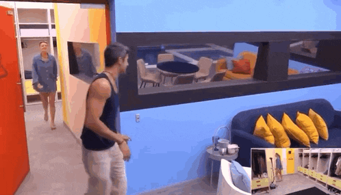 a man in a tank top is walking down a hallway with a woman in the background