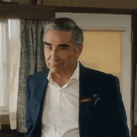 a man in a suit and white shirt is standing in a room in front of a window .