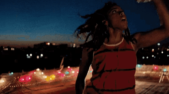a woman in a red dress with her arms up in the air