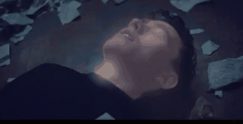 a man is laying on the floor with his eyes closed and a light coming out of his head .