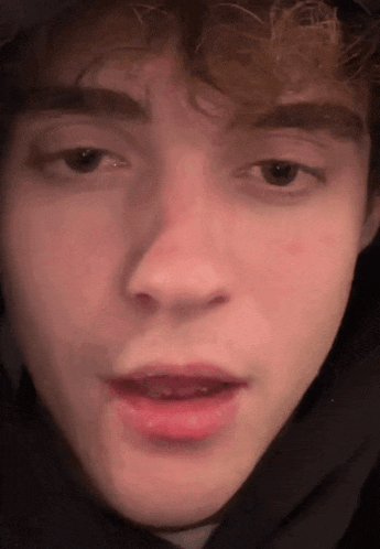 a close up of a young man 's face with a hood on his head .