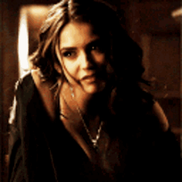 a woman wearing a black shirt and a necklace is looking at the camera