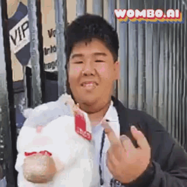 a young man is giving the middle finger while holding a stuffed animal .