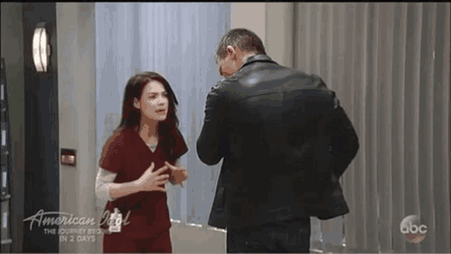 a man and a woman are standing next to each other in a room and talking .