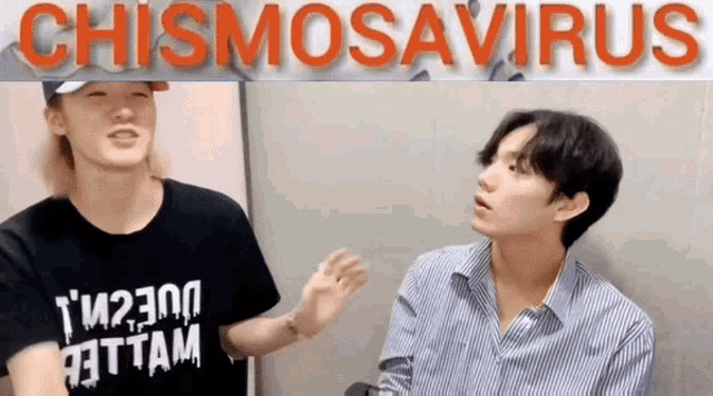 two young men are standing in front of a sign that says chismosavirus