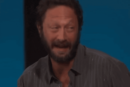 a man with a beard wearing a striped shirt is smiling with his eyes closed