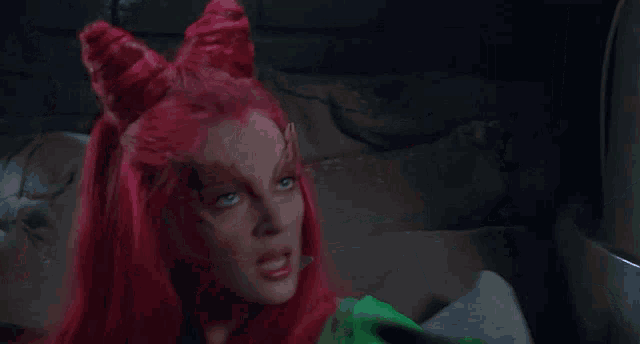 a woman with red hair and a green costume is looking at something