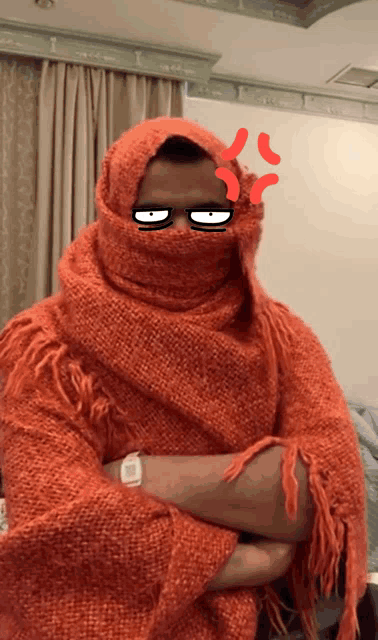 a man wrapped in an orange scarf has an angry face drawn on his forehead
