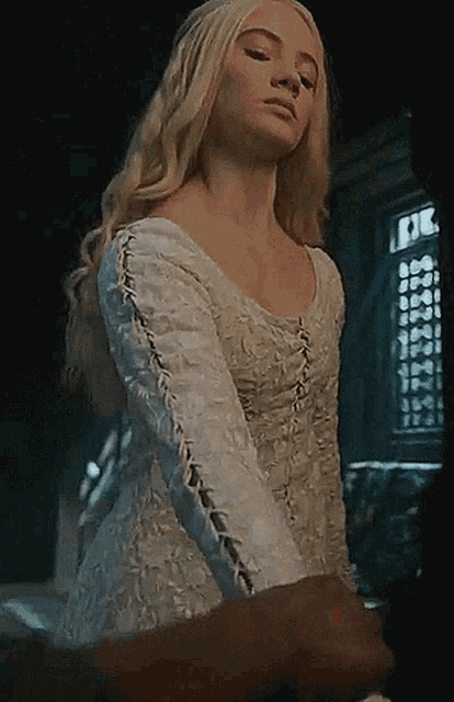 a woman in a white dress is standing in a dark room