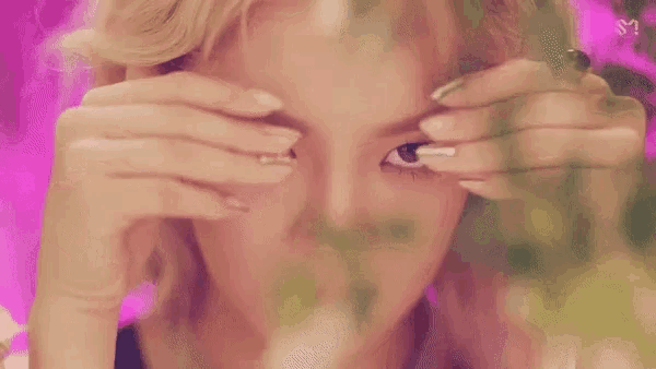 a close up of a woman 's face with a pink background and a blurred background .