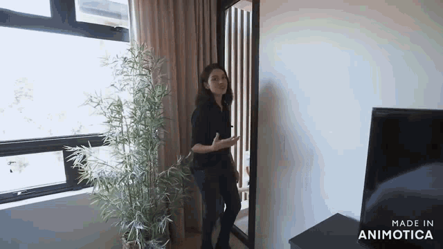 a woman is standing in front of a mirror in a room with a plant .