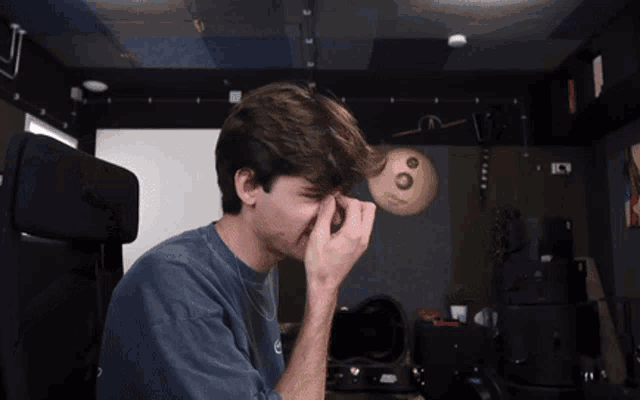 a man covering his eyes with his hands in front of a cymbal that says zildjian