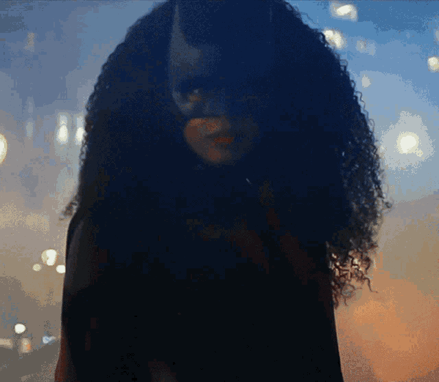 a woman with curly hair wearing a mask