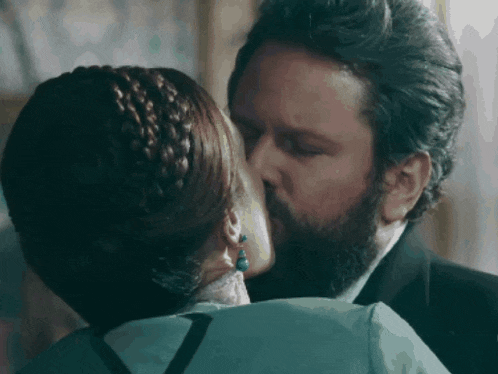 a man and a woman are kissing in a room .