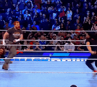 a man in a wrestling ring with a crowd behind him and a sign that says wwe