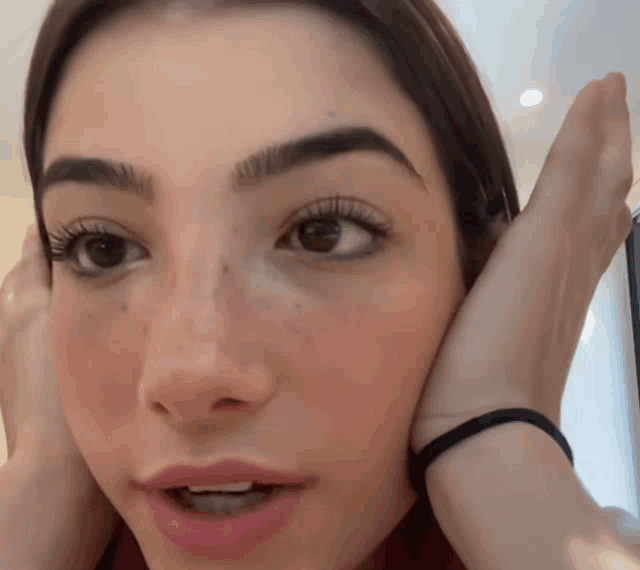 a close up of a woman 's face with her hands on her face