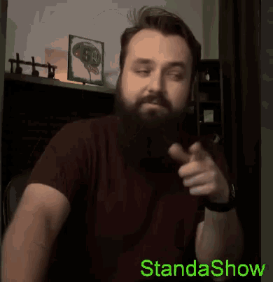 a man with a beard is pointing at the camera with the words standashow written below him