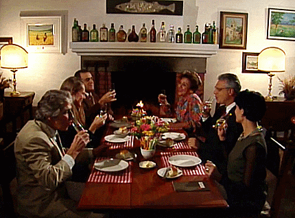 a group of people are sitting around a table with plates and glasses of wine