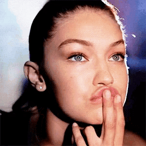 a close up of a woman making a face with her hand on her lips