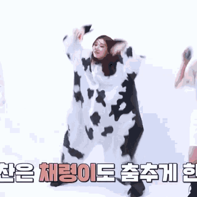 a woman in a cow costume is dancing in front of a white wall .