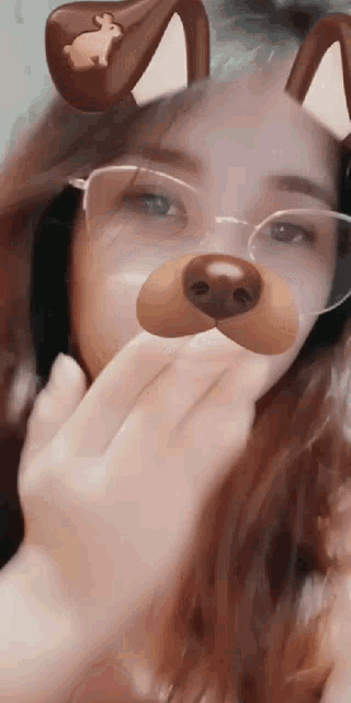 a woman wearing glasses and a dog face mask is covering her mouth .
