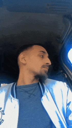a man sitting in a car wearing a blue jacket that says ' du ' on it