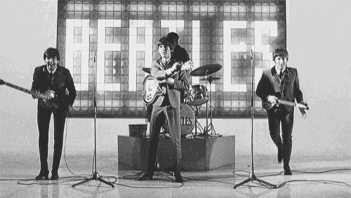 a black and white photo of the beatles performing on stage .