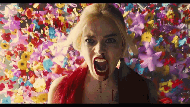 a woman with blood on her face is screaming in front of flowers