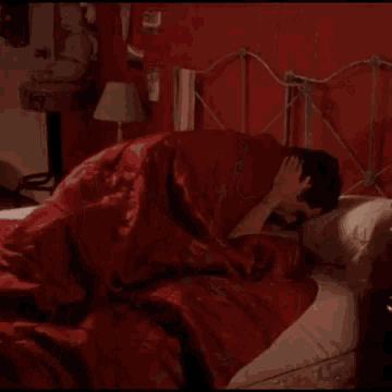 a man in a red robe is laying on a bed and says fifty !!!