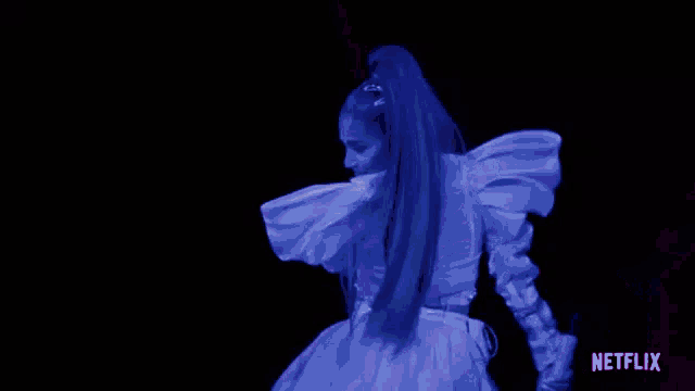 ariana grande is wearing a purple dress and dancing on a stage .