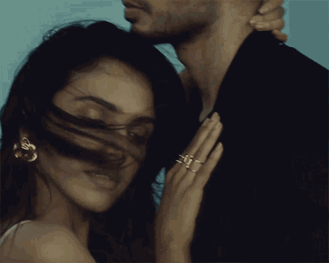 a close up of a woman 's face with a man 's arm around her