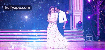 a man and a woman are dancing on a stage with the website kulfyapp.com in the corner .