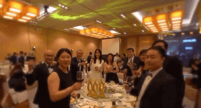 a group of people standing around a table with wine glasses in a large room