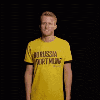a man wearing a yellow t-shirt that says borussia dortmund is making a fist gesture .