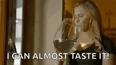 a woman is drinking a large glass of wine and saying `` i can almost taste it ! ''