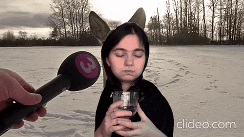 a woman holding a cup in front of a microphone with a 3 on it