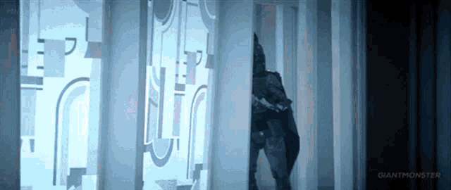 a man in a batman costume is standing in a hallway next to a wall .