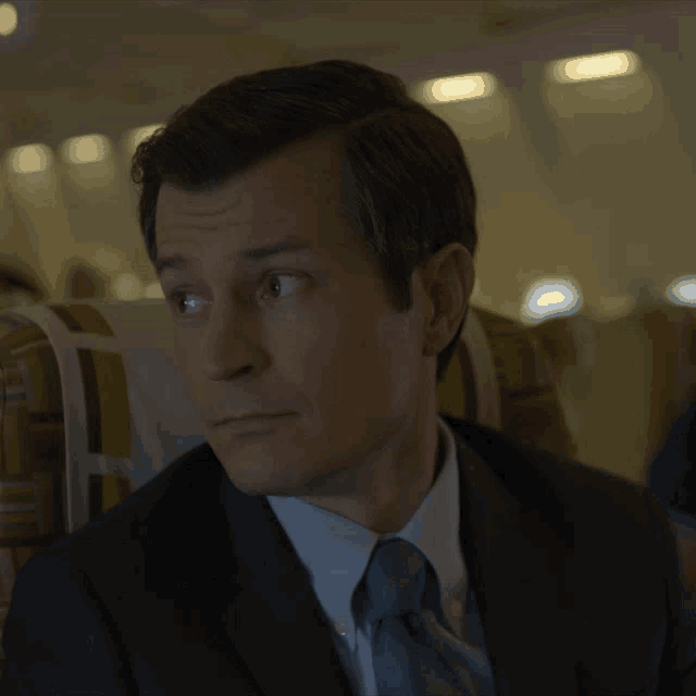 a man in a suit and tie is sitting in a plane