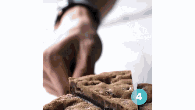 a close up of a person cutting a cookie bar with a blue circle that says 4 on it