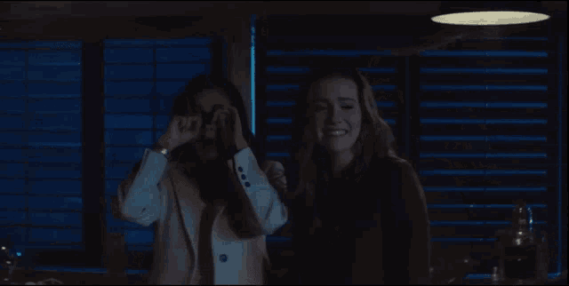 two women are covering their mouths with their hands
