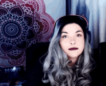 a woman with gray hair is wearing headphones in front of a mandala