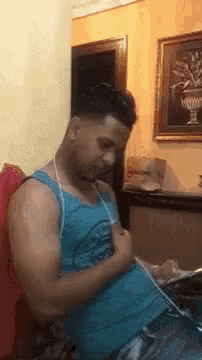 a man is sitting on a couch listening to music on a cell phone .