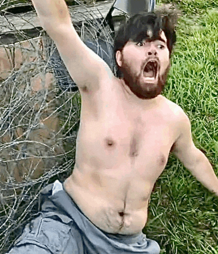 a shirtless man with a beard is laying on the grass with his mouth open